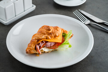 Coffee and croissant sandwich on stone table. French breakfast