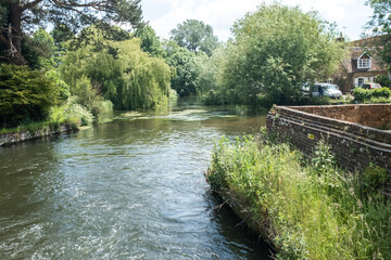 Fototapeta na wymiar Romsey, Hampshire, UK – June 15 2021. The historic Sadler’s Mill on the River Test on the Romsey Heritage trail. Captured on a bright and sunny day