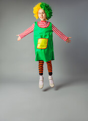 The little girl jumps in a clown uniform