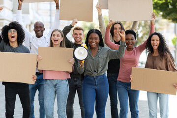 Cheerful multiracial students with blank placards walking by street