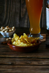 Primer plano de unas patatas fritas acompañados de unos frutos secos y una cerveza