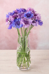 Bouquet of beautiful cornflowers in glass vase on white wooden table