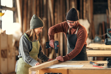 Couple of joiners working with wooden detail in workshop