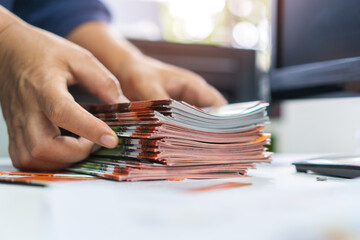 Pile of presentation brochure document concept : Businessman hands working in business Documents on Stacks Brochures papers files for checking achieves reports on busy work computer desk office