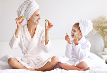 Mother and daughter resting on bed during skin care procedure