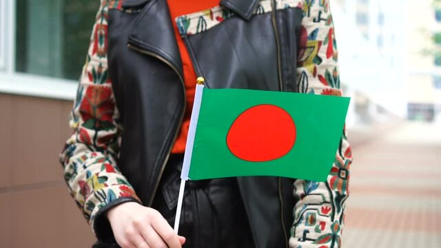 Unrecognizable woman holding Bangladeshi flag. Girl walking down street with national flag of Bangladesh