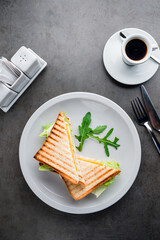Homemade sandwich made of toast bread, fried egg, cheese, lettuce, Sandwich on a white plate