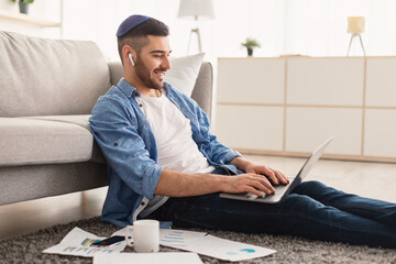 Smiling male jew working on laptop at home