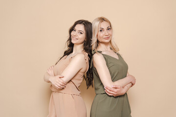 Blonde mother and brunette adult daughter wearing identical clothes, different colors, posing over...