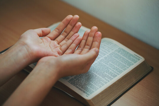 Woman hands praying with an open bible in her room. Concept of learning, education, knowledge, and religion.pray from home