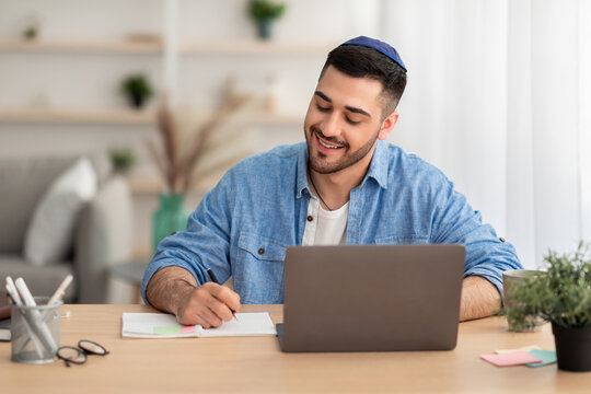 Smiling israeli man working on laptop at home