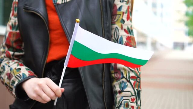 Unrecognizable woman holding Bulgarian flag. Girl walking down street with national flag of Bulgaria