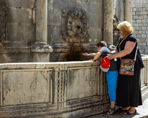 Dubrovnik, tourinsts washing hand in fountain.