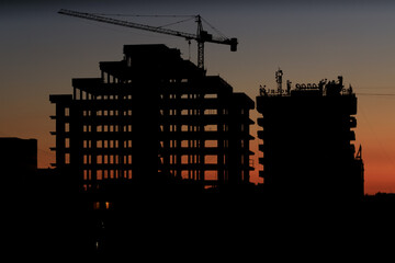 construction of a new building in the city center, an unfinished building at sunset, the silhouette of a building and a crane