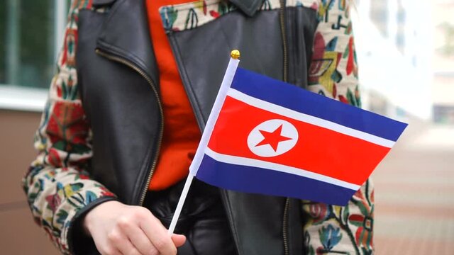 Unrecognizable woman holding Korean flag. Girl walking down street with national flag of North Korea