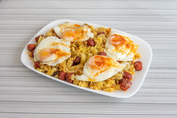 Huge tray to share with broken eggs with chistorra and fried potatoes on a table with black lines