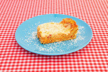 Chicken lasagna with its layers of pasta with béchamel gratin and grated cheese on a blue plate