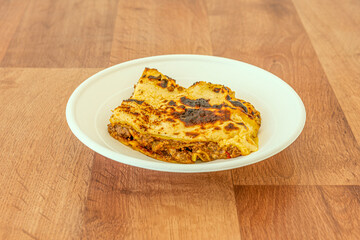Minced meat lasagna with stewed tomato with béchamel sauce and melted cheese on a home delivery container