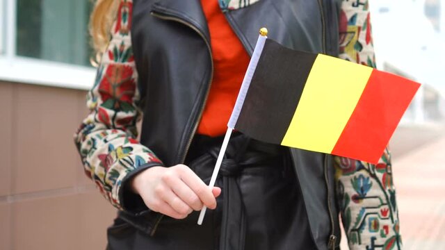 Unrecognizable woman holding Belgian flag. Girl walking down street with national flag of Belgium