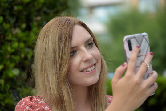 retrato de mujer rubia sonriendo y mirando el teléfono móvil 