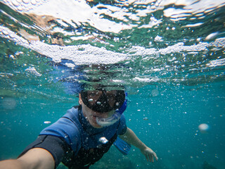Man in snorkel mask doing selfie underwater. Adventure and travel concept.