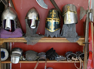 Old medieval helmets and armour displayed on a wooden rack