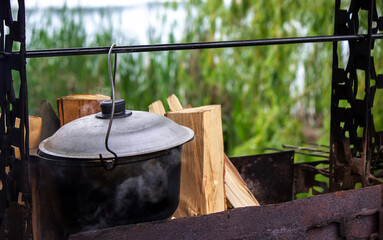 Cooking in cauldron from cast iron on the tripod over the open fire.
