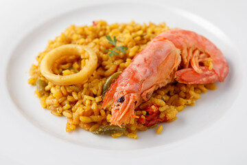 Traditional Spanish paella with seafood and vegetables served on a plate and on a blue table