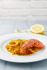 Traditional Spanish paella with seafood and vegetables served on a plate and on a blue table