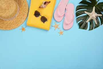 Flat lay composition with beach objects on light blue background, space for text