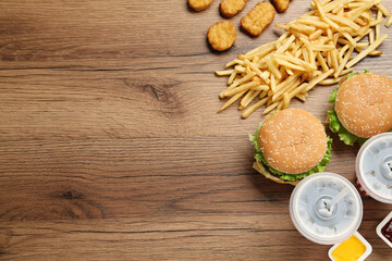 Flat lay composition with delicious fast food menu on wooden table. Space for text