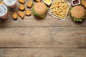 Fototapeta na wymiar Flat lay composition with delicious fast food menu on wooden table. Space for text
