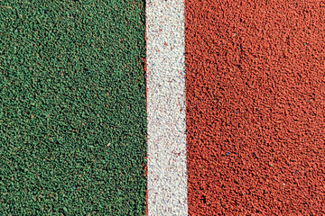 Abstract textured sport field background. Top view of green and red rubber turf surface with white...