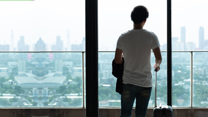 Fototapeta premium Happy Asian man with luggage or suitcase ready to travel for his holidays, tourist holding Passport and Boarding Pass on vacation concept.