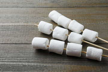 Sticks with sweet marshmallows on wooden table