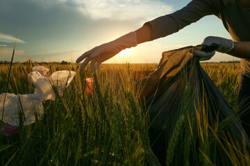 Woman collecting garbage in wheat field, closeup