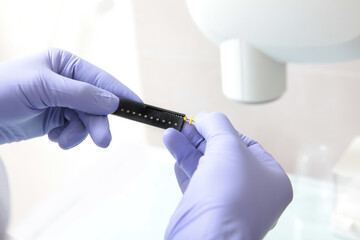 Drill for penetration into the dental canals. The doctor measures the length of the drill. Close-up. Hands in protective gloves.Dental treatment.A ruler in the hands of a doctor.