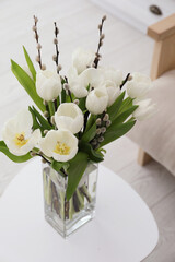 Beautiful bouquet of willow branches and tulips in vase on table indoors, above view