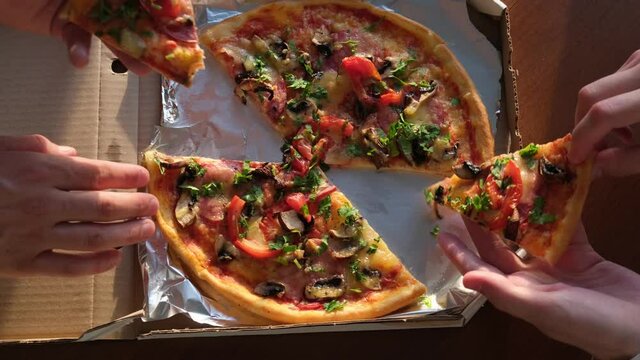 Hands take slices of cheese and tomato pizza from food delivery service
