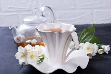 Fototapeta na wymiar Green tea with jasmine in white cup on grey background