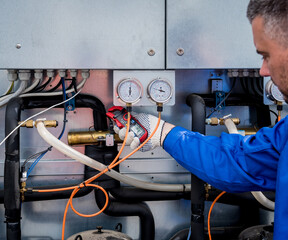 The technician checking power lines of the heat exchanger with current clamps