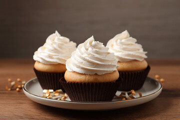 Delicious cupcakes decorated with cream on wooden table