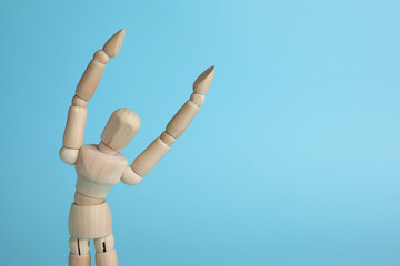 Wooden human model on light blue background, space for text. Mini mannequin