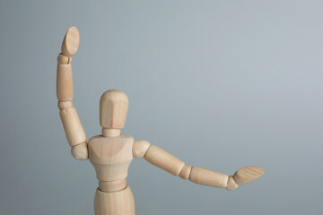 Wooden human model on grey background, space for text. Mini mannequin