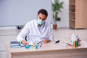 Fototapeta premium Young male chemist teacher sitting in the classroom