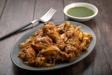 Chilli chicken is a popular Indo-Chinese dish, served on a plate on wooden background
