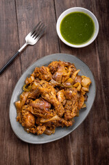 Chilli chicken is a popular Indo-Chinese dish, served on a plate on wooden background
