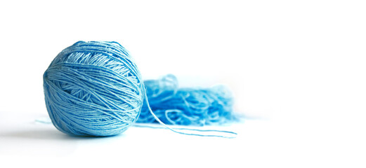 Banner with space for text on the right. The subject of needlework. A ball of blue half-wound fine cotton yarn isolated on a white background. Tangled yarn in the background.