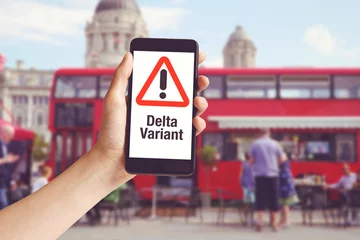 Rolgordijnen Hand met mobiele telefoon met met waarschuwingsbericht delta-variant en rode bus © Daniel Ernst