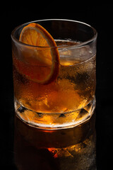 Alcoholic cocktail Old fashioned cocktail with orange slice and lump sugar on black background.